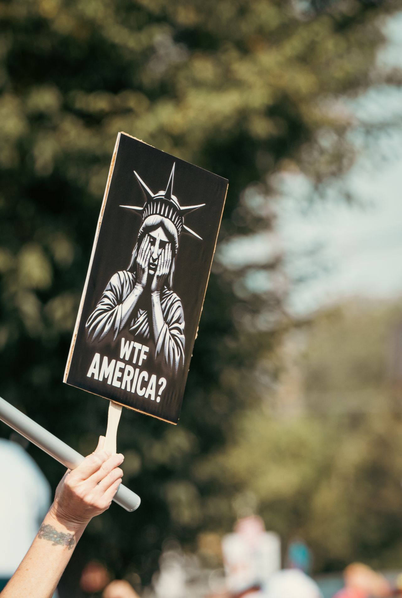 Protester holding a black and white sign of the Statue of Liberty, holding her face in her hands and saying "WTF America?"