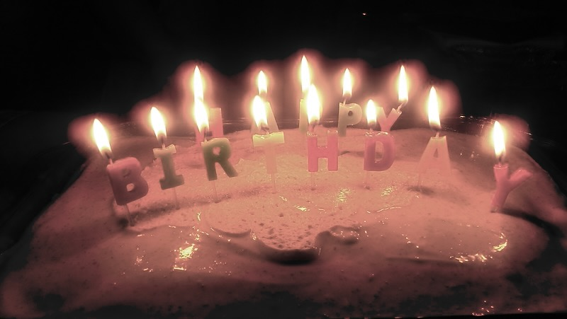 Lighted candles on a cake spelling out HAPPY BIRTHDAY
