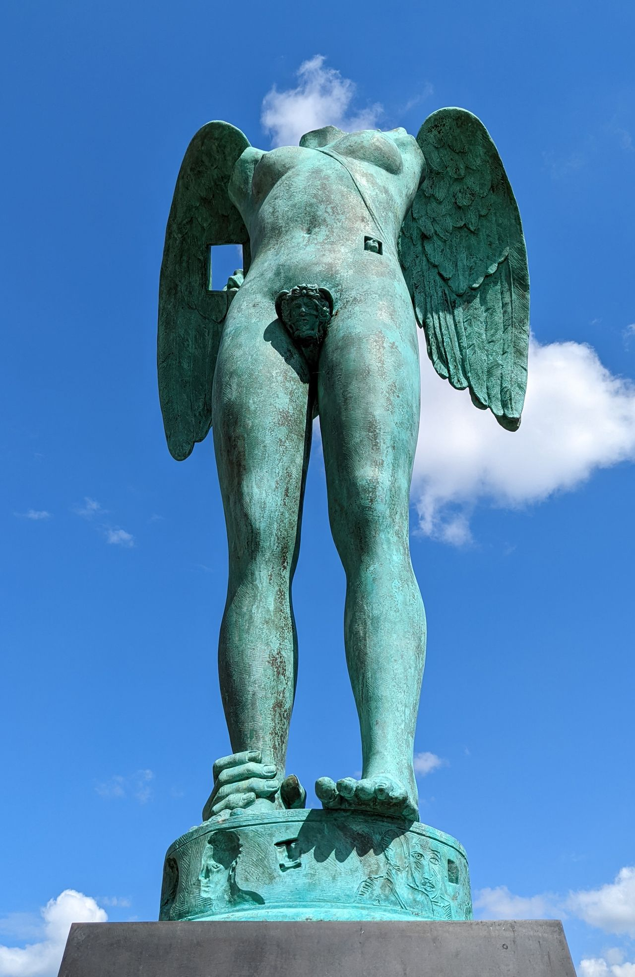Statue of a headless angel with a hand gripping its ankle, holding it rooted to the ground.