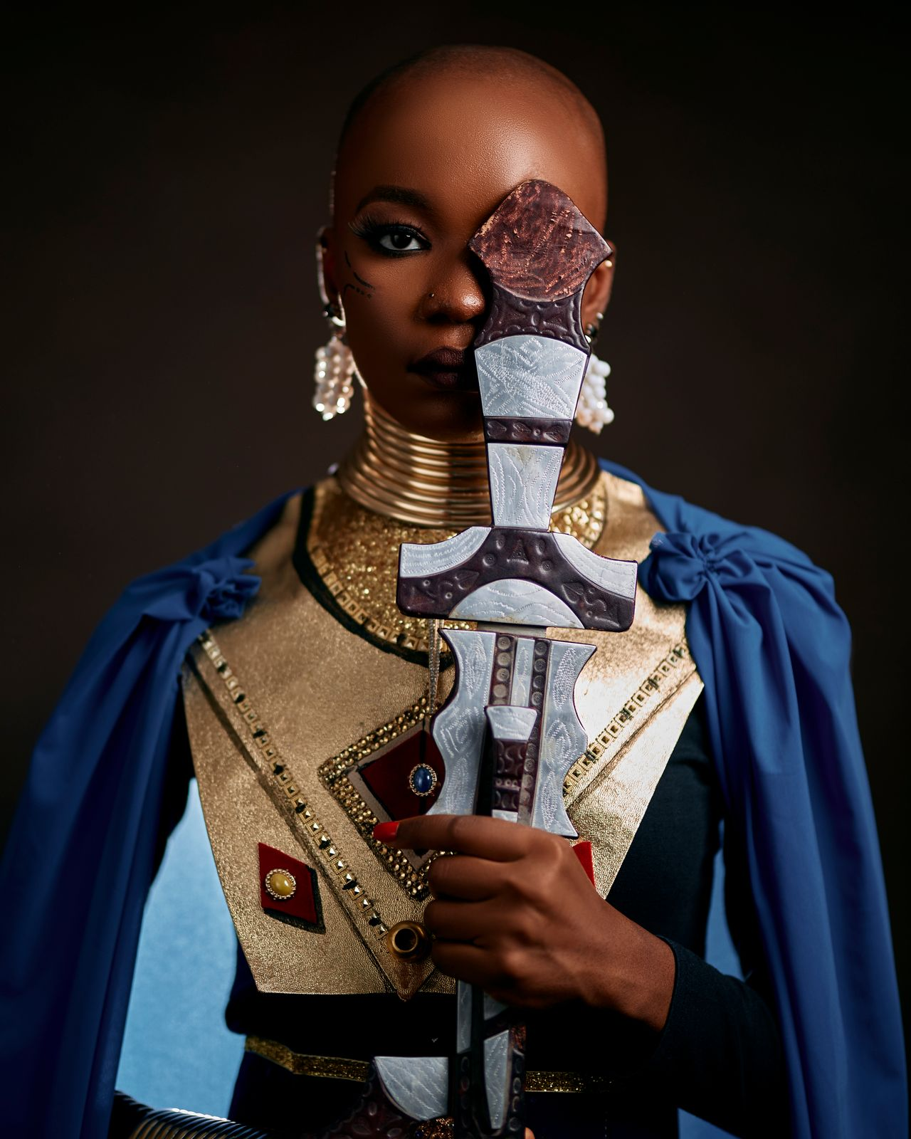 Black woman holding a ceremonial sword and dressed in golden armor