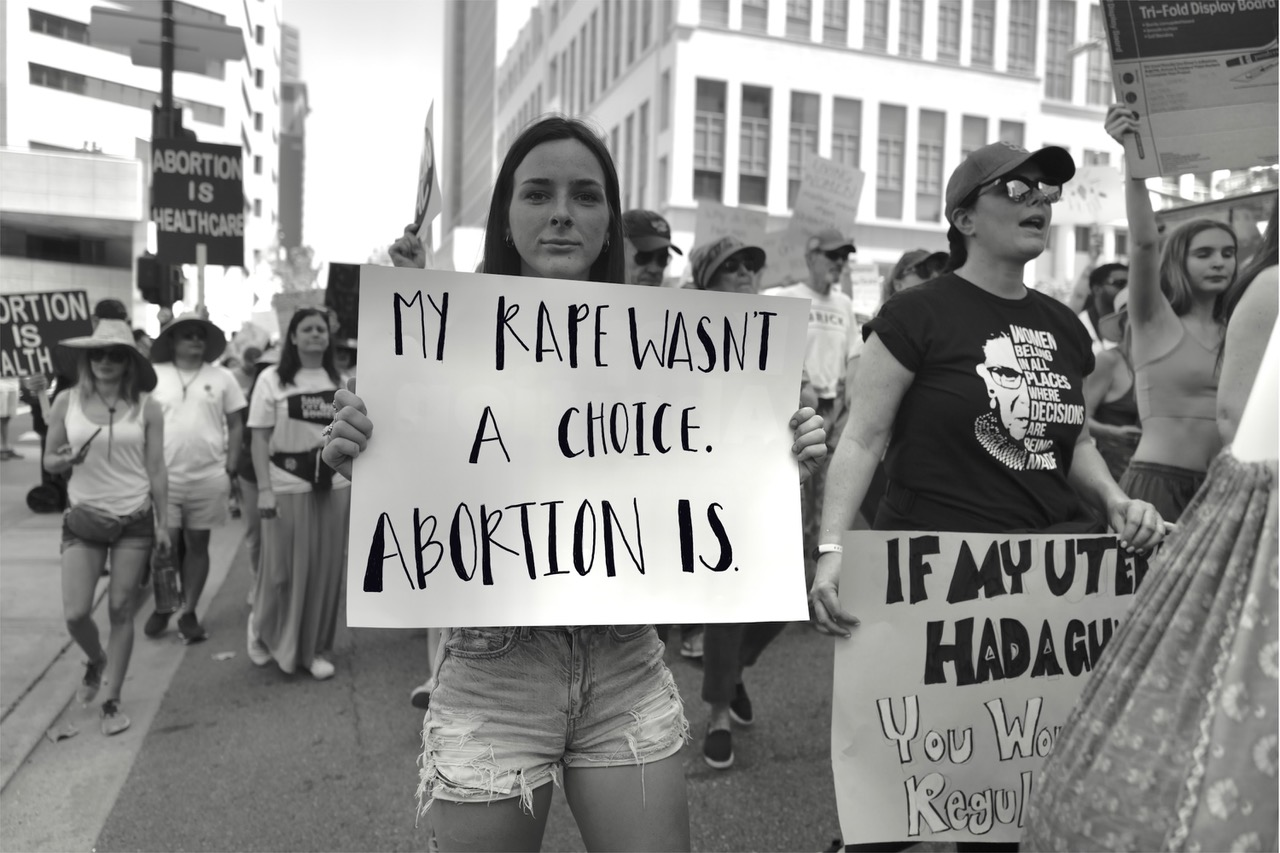 White women holding protest sign that reads "My rape wasn't a choice.Abortion is."