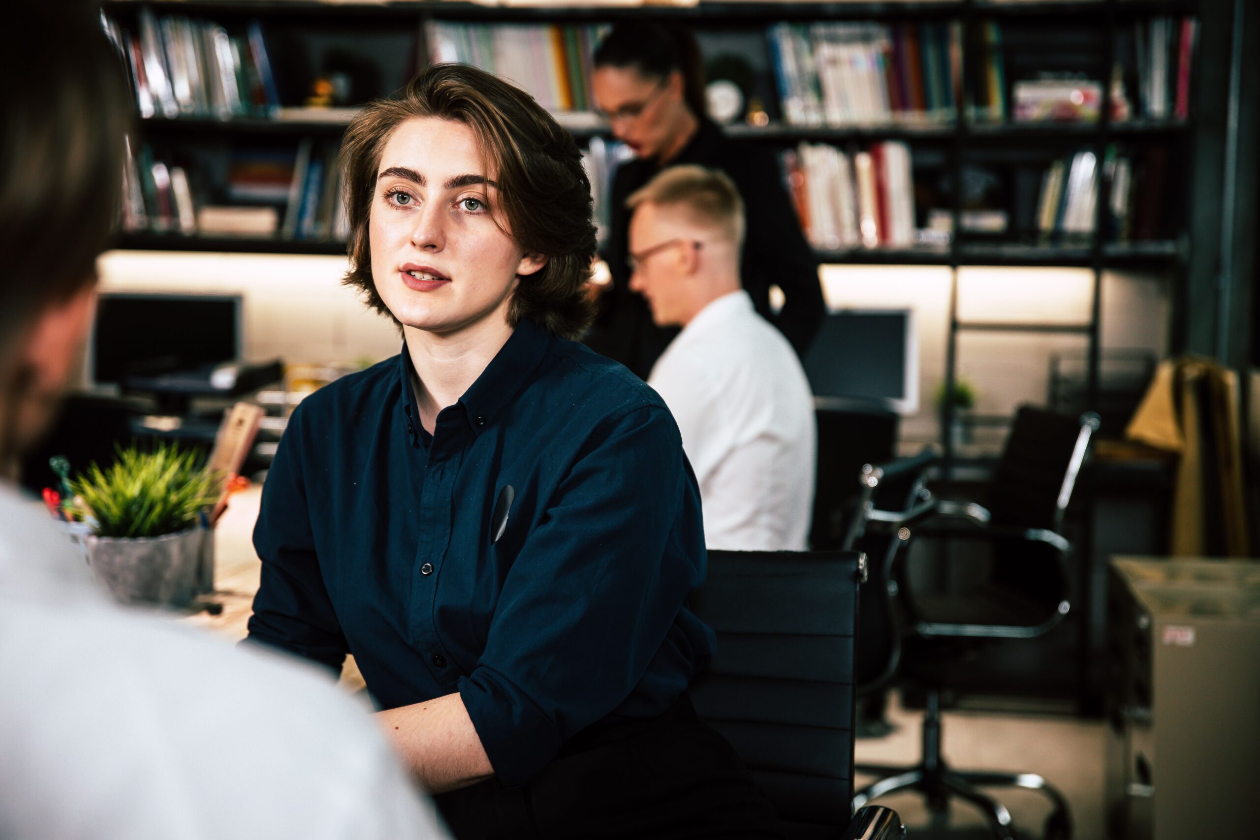 Woman in a black shirt sitting in a work area.