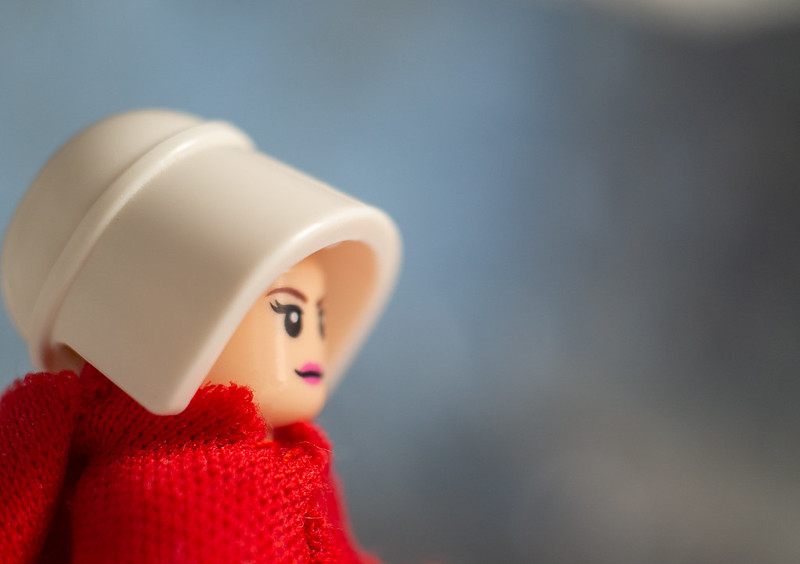 A doll wrapped in red fabric and wearing a white bonnet, reminiscent of The Handmaid's Tale