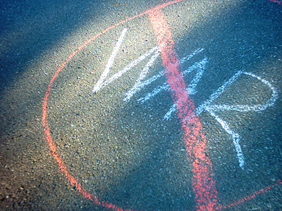 Asphalt road with an anti-war sign chalked on it.