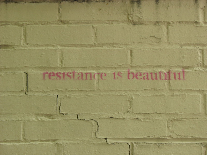 Brick wall with painted words reading resistance is beautiful